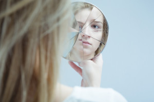Image of woman with mental disorder holding broken mirror